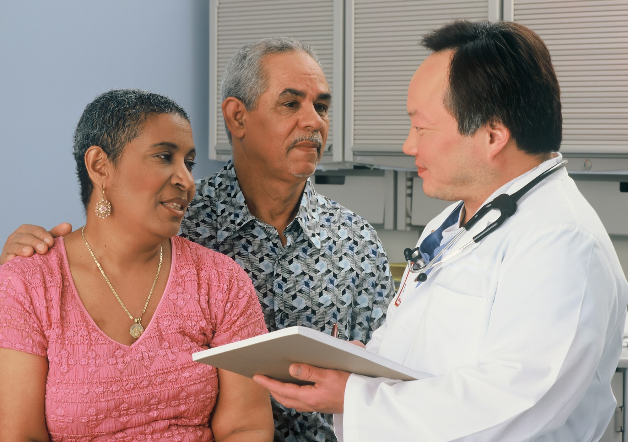 A doctor going over notes with a patient and her husband