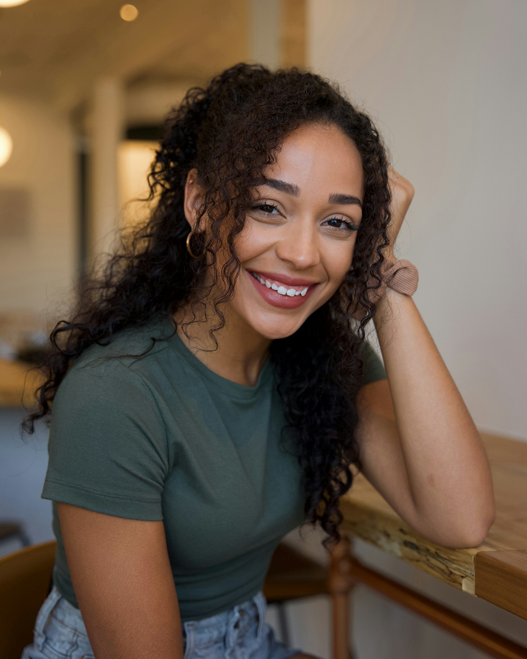 A smiling woman resting her head on her hand
